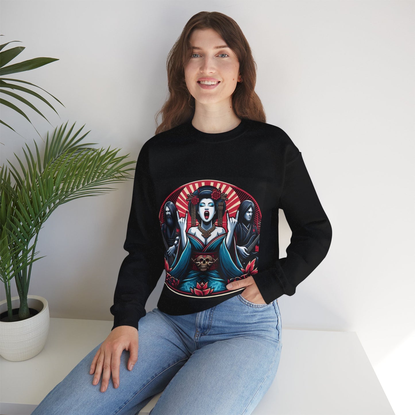 Woman wearing a black gothic sweatshirt with a graphic design sitting on a white surface with a plant in the background.